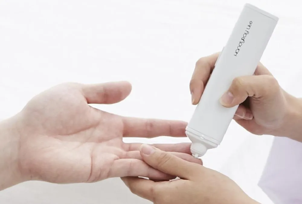 HandyRay-Lite held to a fingertip during a needle-free laser lance